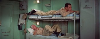 Movie still from “Mister Roberts” (1955), directed by John Ford – Two men are laying on bunk beds in a room; Medium shot, Overhead angle
