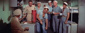 Movie still from “Mister Roberts” (1955), directed by John Ford – A group of men standing next to each other in a room; Medium shot, High angle