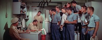 Movie still from “Mister Roberts” (1955), directed by John Ford – A group of men standing in a room next to each other; Medium shot, High angle