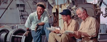 Movie still from “Mister Roberts” (1955), directed by John Ford – Two men are sitting on a boat looking at papers; Medium shot, High angle