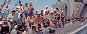 Movie still from “Mister Roberts” (1955), directed by John Ford – A group of men sitting next to each other on a boat; Wide shot, High angle