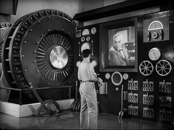 Movie still from “Modern Times” (1936), directed by Charles Chaplin – A man standing in front of a large machine; Wide shot, Over the shoulder angle