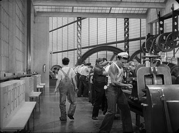 Movie still from “Modern Times” (1936), directed by Charles Chaplin – A group of men working in an industrial setting; Wide shot, High angle