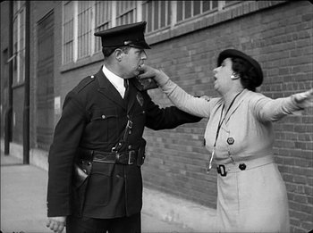 Movie still from “Modern Times” (1936), directed by Charles Chaplin – An old photo of a woman feeding a man a piece of food; Medium shot, Low angle