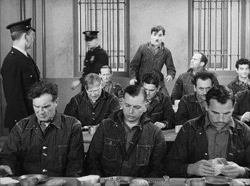 Movie still from “Modern Times” (1936), directed by Charles Chaplin – A black and white photo of a group of men sitting at a table; Medium shot, High angle