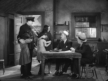 Movie still from “Modern Times” (1936), directed by Charles Chaplin – A group of people standing around a table; Wide shot, Over the shoulder angle
