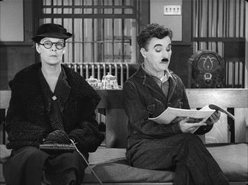 Movie still from “Modern Times” (1936), directed by Charles Chaplin – A couple of men sitting next to each other on a couch; Medium shot, High angle