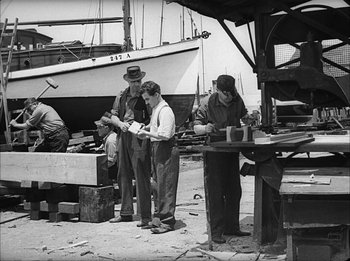 Movie still from “Modern Times” (1936), directed by Charles Chaplin – A group of people standing around a boat; Wide shot, Low angle