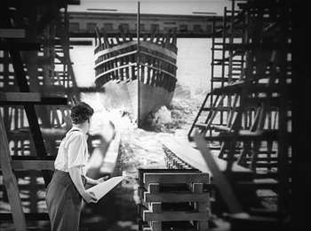 Movie still from “Modern Times” (1936), directed by Charles Chaplin – A man standing in front of a boat in a dock; Wide shot, Low angle