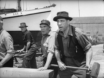 Movie still from “Modern Times” (1936), directed by Charles Chaplin – A group of men standing next to each other on a dock; Medium shot, Low angle
