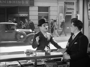 Movie still from “Modern Times” (1936), directed by Charles Chaplin – A man in a top hat talking to another man in a suit; Medium shot, Over the shoulder angle