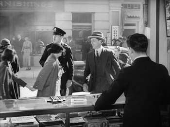 Movie still from “Modern Times” (1936), directed by Charles Chaplin – A group of people standing around a store; Wide shot, Over the shoulder angle
