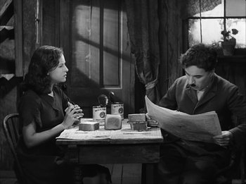 Movie still from “Modern Times” (1936), directed by Charles Chaplin – A man and a woman sitting at a table reading a newspaper; Medium shot, High angle