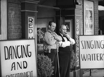 Movie still from “Modern Times” (1936), directed by Charles Chaplin – A couple of men standing next to each other outside; Wide shot, Low angle