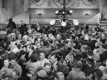 Movie still from “Modern Times” (1936), directed by Charles Chaplin – A large group of people gathered together in a room; Extreme Wide shot, High angle