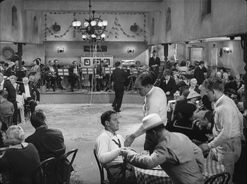 Movie still from “Modern Times” (1936), directed by Charles Chaplin – A group of people sitting in a room with tables; Wide shot, High angle