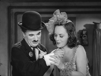 Movie still from “Modern Times” (1936), directed by Charles Chaplin – A man and a woman in a black and white photo; Medium shot, High angle