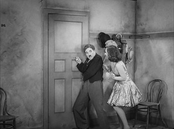 Movie still from “Modern Times” (1936), directed by Charles Chaplin – A man and a woman are standing in front of a door; Wide shot, High angle