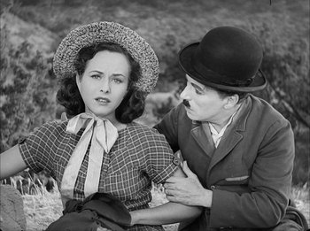 Movie still from “Modern Times” (1936), directed by Charles Chaplin – An old photo of a man and a woman; Medium shot, High angle