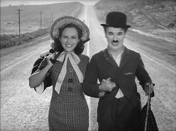 Movie still from “Modern Times” (1936), directed by Charles Chaplin – A man and a woman standing next to each other on the side of a road; Medium shot, High angle