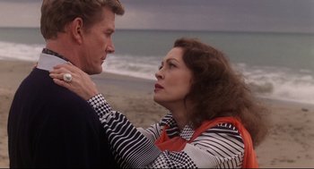 Movie still from “Mommie Dearest” (1981), directed by Frank Perry – A man and a woman standing next to each other on the beach; Medium shot, High angle
