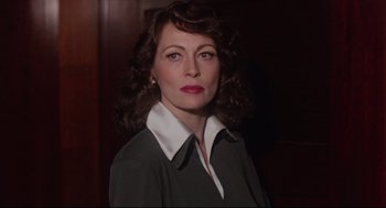 Movie still from “Mommie Dearest” (1981), directed by Frank Perry – A person with curly hair wearing a suit; Close Up shot, Over the shoulder angle