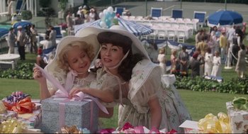 Movie still from “Mommie Dearest” (1981), directed by Frank Perry – A woman and a little girl holding a present; Medium shot, High angle