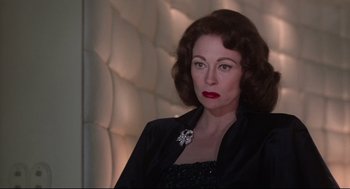 Movie still from “Mommie Dearest” (1981), directed by Frank Perry – An older woman wearing a black jacket and red lipstick; Close Up shot, Low angle