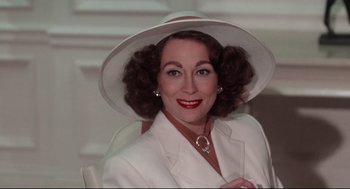 An older woman wearing a white suit and a hat