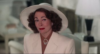 Movie still from “Mommie Dearest” (1981), directed by Frank Perry – A woman in a white suit and a white hat; Close Up shot, Over the shoulder angle