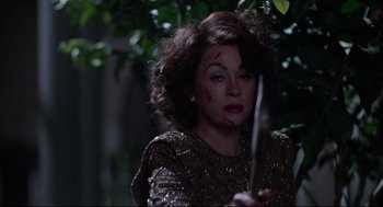 Movie still from “Mommie Dearest” (1981), directed by Frank Perry – A woman holding a knife with blood all over her face; Close Up shot, High angle