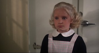 Movie still from “Mommie Dearest” (1981), directed by Frank Perry – A young girl with blonde ringlet hair wearing a plaid apron; Close Up shot, High angle