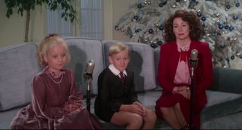 Movie still from “Mommie Dearest” (1981), directed by Frank Perry – A group of people that are sitting on a couch; Medium shot, High angle