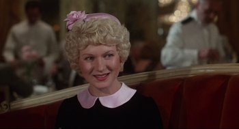 Movie still from “Mommie Dearest” (1981), directed by Frank Perry – A woman with blonde curly hair and a pink flower in her hair; Close Up shot, Over the shoulder angle