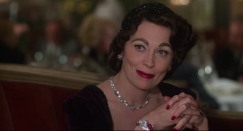 Movie still from “Mommie Dearest” (1981), directed by Frank Perry – A person wearing a hat and a necklace; Close Up shot, Over the shoulder angle