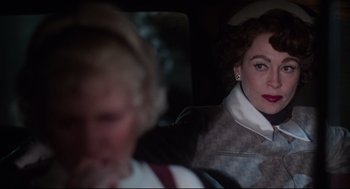 Movie still from “Mommie Dearest” (1981), directed by Frank Perry – A woman sitting in the back seat of a car; Close Up shot, Over the shoulder angle