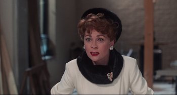 Movie still from “Mommie Dearest” (1981), directed by Frank Perry – An older woman wearing a white jacket and a black hat; Close Up shot, Over the shoulder angle