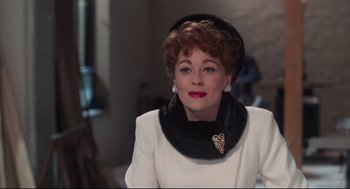Movie still from “Mommie Dearest” (1981), directed by Frank Perry – An older woman wearing a white dress and a black hat; Close Up shot, Over the shoulder angle