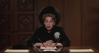 A woman sitting at a table with a pen in her hand
