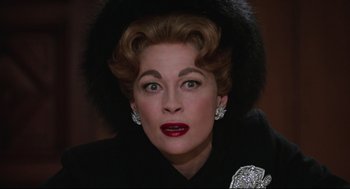 Movie still from “Mommie Dearest” (1981), directed by Frank Perry – An older woman wearing a black coat and a black hat; Close Up shot, Low angle
