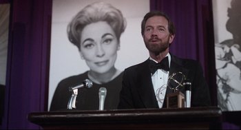 A man standing in front of a picture of a woman
