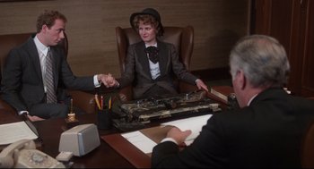 Movie still from “Mommie Dearest” (1981), directed by Frank Perry – A woman sitting at a table in front of two other people; Medium shot, High angle