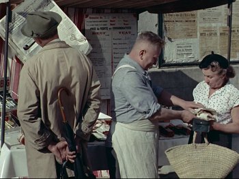 Movie still from “My Uncle” (1958), directed by Jacques Tati – An old photo of a man and a woman at an outdoor market; Medium shot, High angle