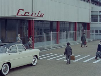 Movie still from “My Uncle” (1958), directed by Jacques Tati – A man walking down the street with a suitcase; Extreme Wide shot, High angle