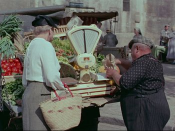 Movie still from “My Uncle” (1958), directed by Jacques Tati – Two men standing in front of an outdoor produce stand; Medium shot, High angle
