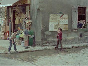 Movie still from “My Uncle” (1958), directed by Jacques Tati – A group of young boys standing next to each other on a sidewalk; Wide shot, High angle