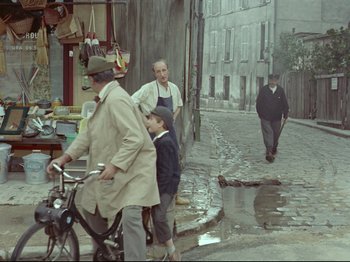 Movie still from “My Uncle” (1958), directed by Jacques Tati – A group of people walking down a street; Wide shot, High angle