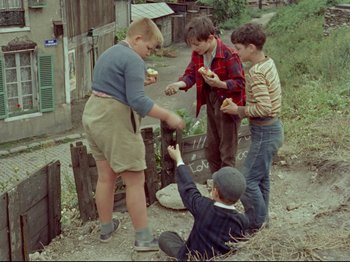 Movie still from “My Uncle” (1958), directed by Jacques Tati – A group of kids standing around eating food; Wide shot, High angle