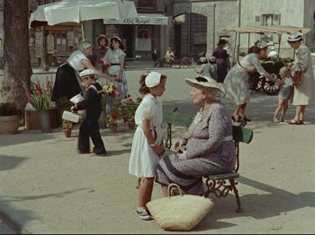 Movie still from “My Uncle” (1958), directed by Jacques Tati – An older woman sitting on a bench talking to a young girl; Wide shot, High angle