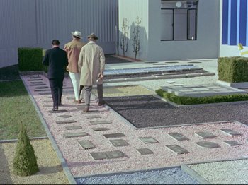 Movie still from “My Uncle” (1958), directed by Jacques Tati – A group of people walking down a sidewalk; Extreme Wide shot, High angle